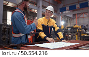 Team of engineers and architects working with blueprint at factory site. It is a massive new facility for making metal sheets as well as a transportation and distribution warehouse. Стоковое фото, агентство Ingram Publishing / Фотобанк Лори