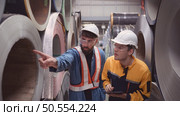 A team of young men working in a warehouse storing rolls of metal sheets. Inspecting the metal sheet rolls stored in the warehouse to be imported onto the metal sheet production line. Стоковое фото, агентство Ingram Publishing / Фотобанк Лори