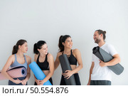 A group of female and male athletes stood and chatted amicably in the studio before beginning with the yoga class. Стоковое фото, агентство Ingram Publishing / Фотобанк Лори