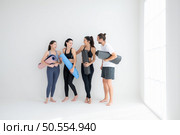 A group of female and male athletes stood and chatted amicably in the studio before beginning with the yoga class. Стоковое фото, агентство Ingram Publishing / Фотобанк Лори