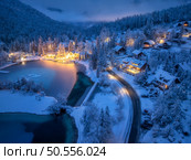 Aerial view of fairy alpine village in snow, road, forest, Jasna lake, houses, street lights at winter night. Top view of mountains, illumination, snowy pine trees at twilight. Kranjska Gora, Slovenia. Стоковое фото, агентство Ingram Publishing / Фотобанк Лори
