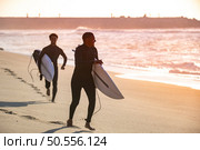 Two surfers run in the beach near the ocean with surfboard. Стоковое фото, агентство Ingram Publishing / Фотобанк Лори