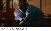 Welder in protective uniform and mask welding metal pipe on the industrial table while sparks flying. Стоковое фото, агентство Ingram Publishing / Фотобанк Лори