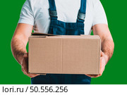 Young delivery man hold a cardboard box in his hands with Green Screen chroma key ultra key. Стоковое фото, агентство Ingram Publishing / Фотобанк Лори