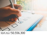 Close- up hand holding pen on check list paper and the format for filling in information in business concept, vintage style and softtone. Стоковое фото, агентство Ingram Publishing / Фотобанк Лори