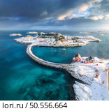 Aerial view of road and bridges, snowy rocks, islands with rorbu, sea, water, mountains, cloudy sky at sunset in winter. Beautiful north landscape. Top view of Henningsvaer, Lofoten islands, Norway. Стоковое фото, агентство Ingram Publishing / Фотобанк Лори