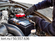 A man wearing gloves securely fastens a car battery terminal after installing it under the hood. Replacing a weak battery. Стоковое фото, фотограф Коханова Наталья / Фотобанк Лори
