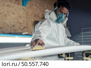 Surfboard manufacturing, Shaper working on board details. Concept of industrial manufacturing, qualified professional, occupation and employment. Стоковое фото, агентство Ingram Publishing / Фотобанк Лори