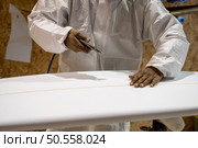 Surfboard manufacturing, Shaper working on board details. Concept of industrial manufacturing, qualified professional, occupation and employment. Стоковое фото, агентство Ingram Publishing / Фотобанк Лори