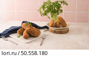 Cod dumplings, or "bolinhos de bacalhau" and parsley leaves on white ceramic dishes in a kitchen counter top. Стоковое фото, агентство Ingram Publishing / Фотобанк Лори
