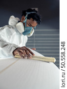 Surfboard manufacturing, Shaper working on board details. Concept of industrial manufacturing, qualified professional, occupation and employment. Стоковое фото, агентство Ingram Publishing / Фотобанк Лори