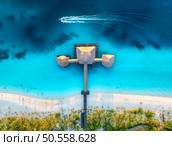 Aerial view of bungalow, boat in Indian Ocean at sunset in summer. Restaurant on the sea. Top drone view of wooden hotel, azure water, white sandy beach, palm trees. Luxury resort in Kendwa, Zanzibar. Стоковое фото, агентство Ingram Publishing / Фотобанк Лори
