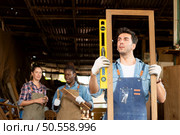 Portrait of carpenter male worker standing in front of colleague in workshop, Eyesight is utilized to ensure accuracy. Стоковое фото, агентство Ingram Publishing / Фотобанк Лори
