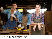 Portrait of carpenter female worker standing in front of colleague in workshop, Eyesight is utilized to ensure accuracy. Стоковое фото, агентство Ingram Publishing / Фотобанк Лори