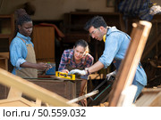 Carpenter and his assistant working together in a carpentry workshop. Стоковое фото, агентство Ingram Publishing / Фотобанк Лори