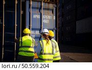 Group of workers in an empty container storage yard, The condition of the old container is being assessed to determine whether it requires maintenance for usage. Стоковое фото, агентство Ingram Publishing / Фотобанк Лори