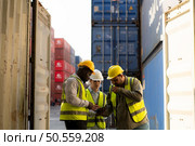 Group of workers in an empty container storage yard, The condition of the old container is being assessed to determine whether it requires maintenance for usage. Стоковое фото, агентство Ingram Publishing / Фотобанк Лори