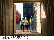 Group of workers in an empty container storage yard, The condition of the old container is being assessed to determine whether it requires maintenance for usage. Стоковое фото, агентство Ingram Publishing / Фотобанк Лори