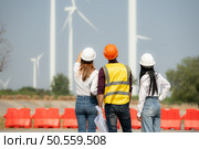 Back view of group engineers and architects on construction site with wind turbines in background. Стоковое фото, агентство Ingram Publishing / Фотобанк Лори