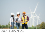 Group of engineers and architects on construction site with wind turbines in background. Стоковое фото, агентство Ingram Publishing / Фотобанк Лори