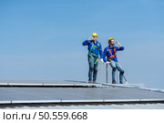 Both of technician repairing solar panels rest in the scorching sun on a factory roof covered with solar panels to receive solar energy. Стоковое фото, агентство Ingram Publishing / Фотобанк Лори
