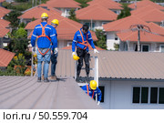 After installing and inspecting the performance of the solar cell panels on the factory roof, a group of engineers installing solar panels descends the stairs to go home. Стоковое фото, агентство Ingram Publishing / Фотобанк Лори