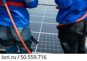 Both of technicians is installing solar panels on the roof of the warehouse to change solar energy into electrical energy for use in factories. Стоковое фото, агентство Ingram Publishing / Фотобанк Лори