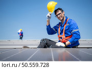 Technician repairing solar panels take off his hat and rest in the scorching sun on a factory roof covered with solar panels to receive solar energy. Стоковое фото, агентство Ingram Publishing / Фотобанк Лори