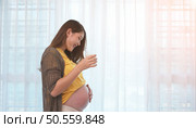 Pregnant asian woman holding glass of milk and smiles happily talking to her unborn child. Стоковое фото, агентство Ingram Publishing / Фотобанк Лори