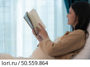 Pregnant woman reading a stories to her unborn child in the living room at home. Стоковое фото, агентство Ingram Publishing / Фотобанк Лори