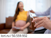 Obstetrician gynecologist and vaccination needle or pregnant woman, Asian pregnant woman visit gynecologist doctor at medical clinic for pregnancy consultant. Стоковое фото, агентство Ingram Publishing / Фотобанк Лори