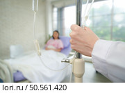 Female doctor with IV equipment will give IV fluids and examine patients lying in hospital beds. Стоковое фото, агентство Ingram Publishing / Фотобанк Лори