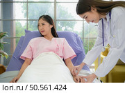 Female doctor with IV equipment will give IV fluids and examine patients lying in hospital beds. Стоковое фото, агентство Ingram Publishing / Фотобанк Лори
