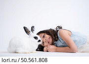 A little girl kisses her beloved fluffy rabbit, The beauty of friendship between humans and animals. Стоковое фото, агентство Ingram Publishing / Фотобанк Лори
