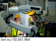Technician who maintains a small robot arm the operation of a small robot arm used in industry is being repaired. Стоковое фото, агентство Ingram Publishing / Фотобанк Лори