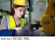 Female technician who maintains a small robot arm the operation of a small robot arm used in industry is being repaired. Стоковое фото, агентство Ingram Publishing / Фотобанк Лори