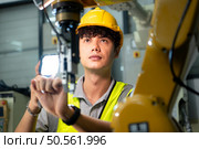 Technician who maintains a small robot arm the operation of a small robot arm used in industry is being repaired. Стоковое фото, агентство Ingram Publishing / Фотобанк Лори