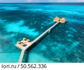 Aerial view of bungalow, jetty, sandy beach, ocean on summer sunny day. Restaurant on the blue sea. Top drone view of wooden hotel, azure water. Luxury resort in Zanzibar. Tropical background. Travel. Стоковое фото, агентство Ingram Publishing / Фотобанк Лори