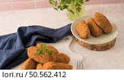 Cod dumplings, or "bolinhos de bacalhau" and parsley leaves on white ceramic dishes in a kitchen counter top. Стоковое фото, агентство Ingram Publishing / Фотобанк Лори