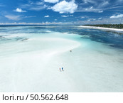 Aerial view of island during low tide, sandbank in ocean, white sandy beach, people, blue sea at sunny summer day in Zanzibar. Top view of sand spit, clear water, sky with clouds. Tropical background. Стоковое фото, агентство Ingram Publishing / Фотобанк Лори