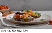 Italian bruschettas with roasted tomatoes, mozzarella cheese, pineapple slices and herbs on a rustic kitchen countertop. Стоковое фото, агентство Ingram Publishing / Фотобанк Лори