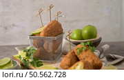 Cod dumplings, or "bolinhos de bacalhau" and parsley leaves and lemons on wooden cutting board in a kitchen counter top. Стоковое фото, агентство Ingram Publishing / Фотобанк Лори