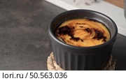 A close-up of a creme brulee in a black ramekin on a woven coaster. Стоковое фото, агентство Ingram Publishing / Фотобанк Лори