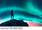 Aurora borealis and sporty woman on mountain peak at night. Northern lights and silhouette of a girl on top of rock. Lofoten islands, Norway. Landscape with polar lights. Starry sky with bright aurora. Northern lights and woman on mountain peak at night. Aurora. Стоковое фото, агентство Ingram Publishing / Фотобанк Лори