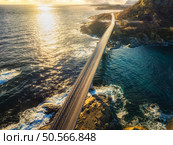 Aerial view of djupfjordbrua bridge connecting Moskenes island to the mainland, blue ocean water and rocky coastline in Lofoten archipelago, Norway at sunset. Top drone view of road, rocks in sea. Стоковое фото, агентство Ingram Publishing / Фотобанк Лори