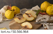 Ripe yellow quinces or queen apple fruits and sliced quince halves with seeds in craft cork plates on black rustic background. Стоковое фото, агентство Ingram Publishing / Фотобанк Лори