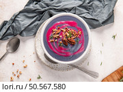 Creamy purple soup garnished with pecans and rosemary in a white bowl, presented on a speckled plate with a gray cloth napkin and a spoon. Стоковое фото, агентство Ingram Publishing / Фотобанк Лори