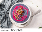 Vibrant purple soup with a swirl of pink, topped with pecans and rosemary, served in a white bowl on a speckled plate with a gray cloth napkin. Стоковое фото, агентство Ingram Publishing / Фотобанк Лори