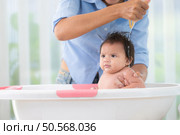 A mother bathes her little daughter in a small children’s tub. Стоковое фото, агентство Ingram Publishing / Фотобанк Лори