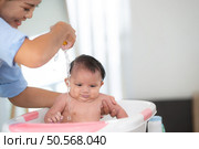 A mother bathes her little daughter in a small children’s tub. Стоковое фото, агентство Ingram Publishing / Фотобанк Лори